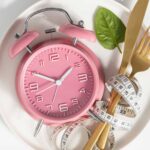 assiette rempli de couvert et d'un réveil rose