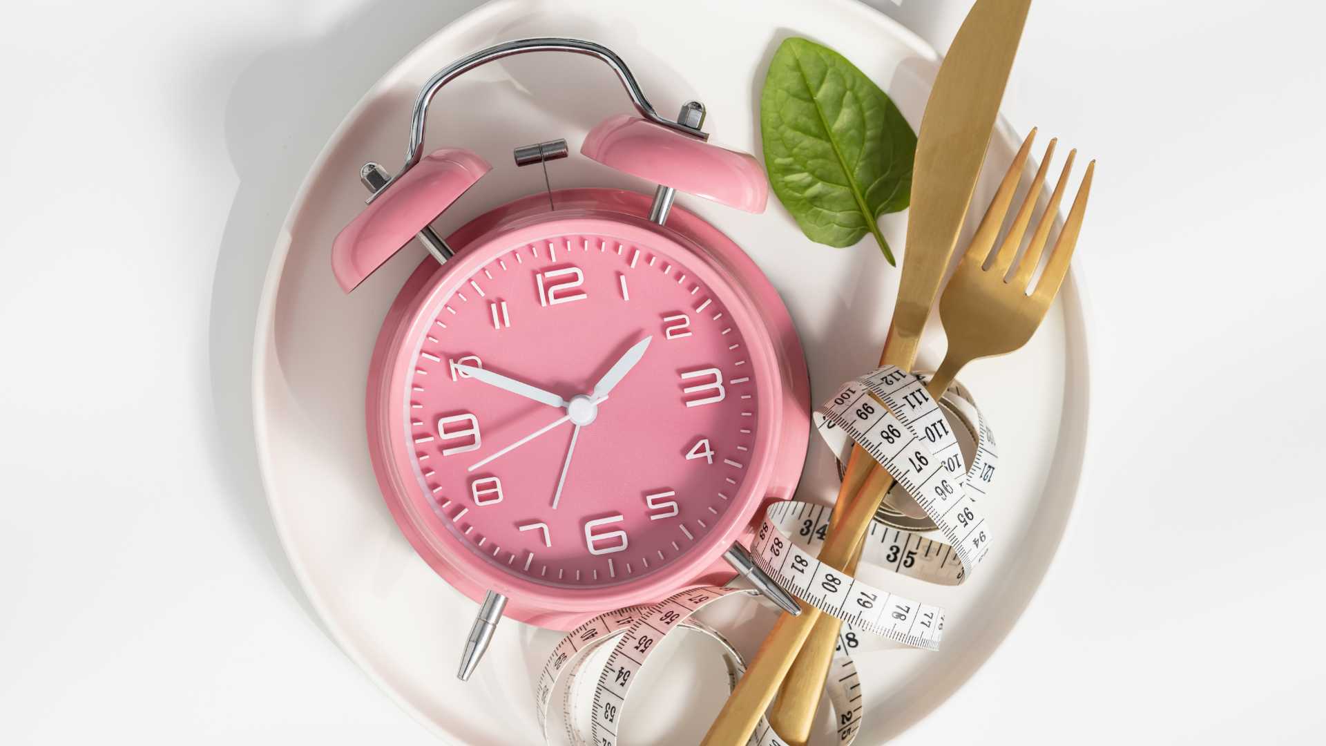 assiette rempli de couvert et d'un réveil rose